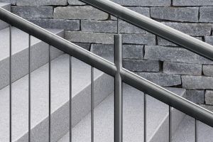 Edelstahl-Treppengeländer vor einer Natursteinwand