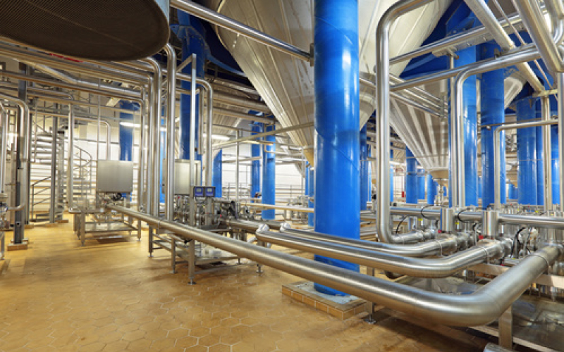 Industrieanlage mit blauen Stahlsäulen und Edelstahlrohrleitungen