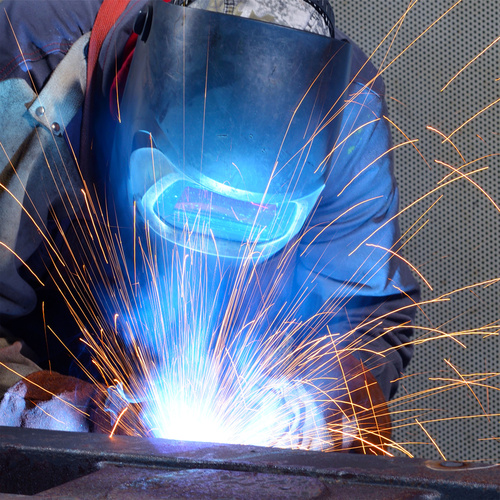 Schweißer bei der Arbeit mit Schutzhelm und Funkenflug