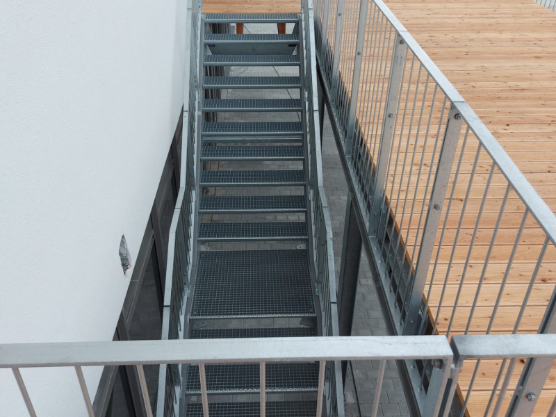 Blick von oben auf Stahltreppe mit Holzterrasse und Geländer