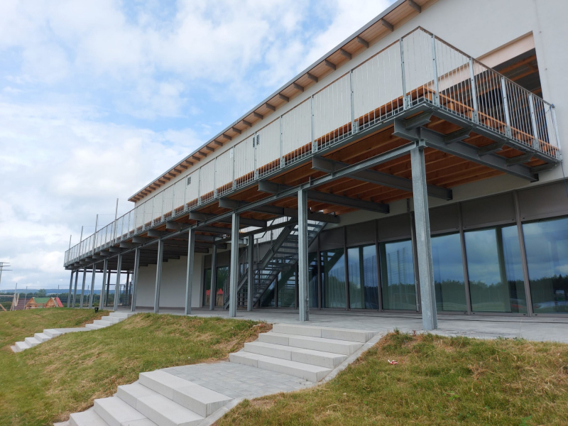 Stahlbalkon mit Holzbelag und Geländer an Gewerbegebäude