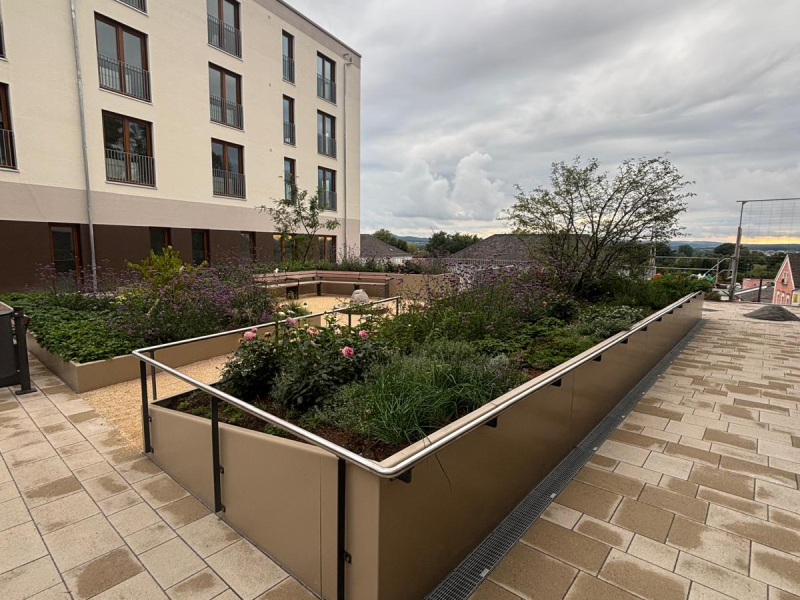 Langes Cortenstahl-Hochbeet entlang einer Gebäudefassade