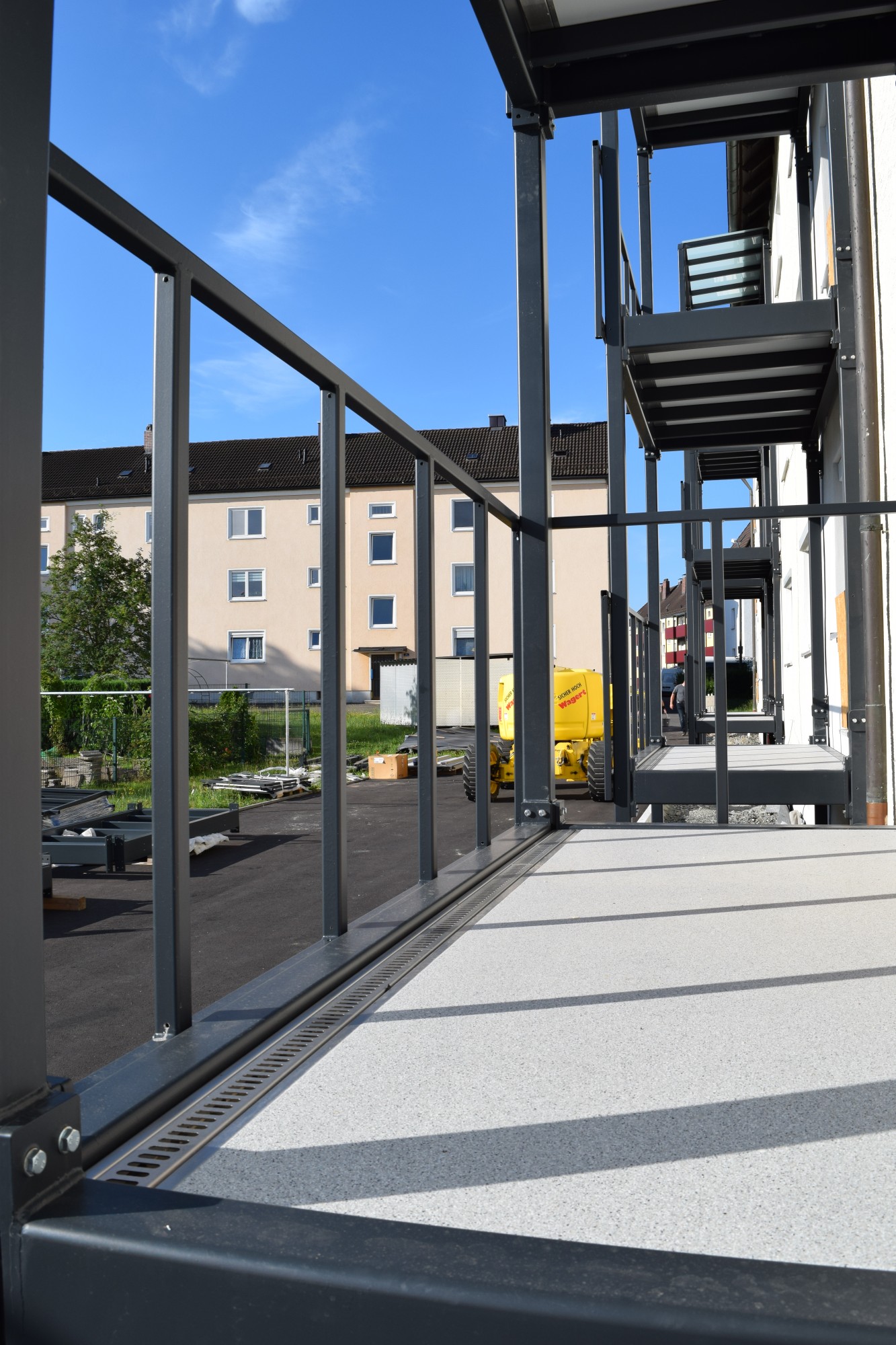 Nahaufnahme eines Stahlbalkons mit Glasgeländer und Entwässerungsrinne