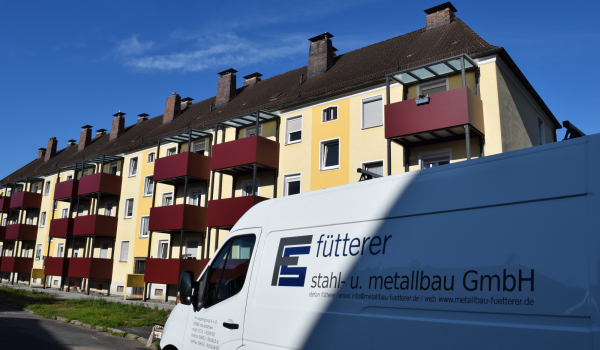 Firmenfahrzeug vor Wohnhaus mit neu montierten Stahlbalkonen