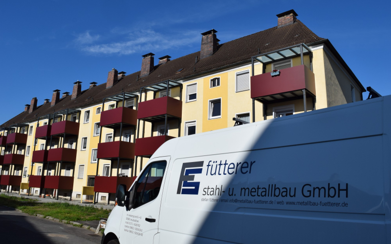 Firmenfahrzeug vor Wohnhaus mit neu montierten Stahlbalkonen