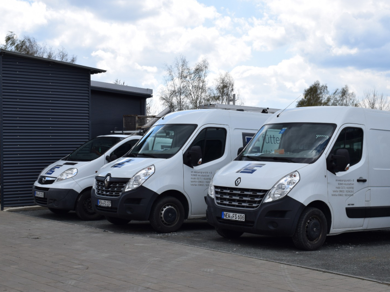 Drei Firmenfahrzeuge vor der Werkhalle